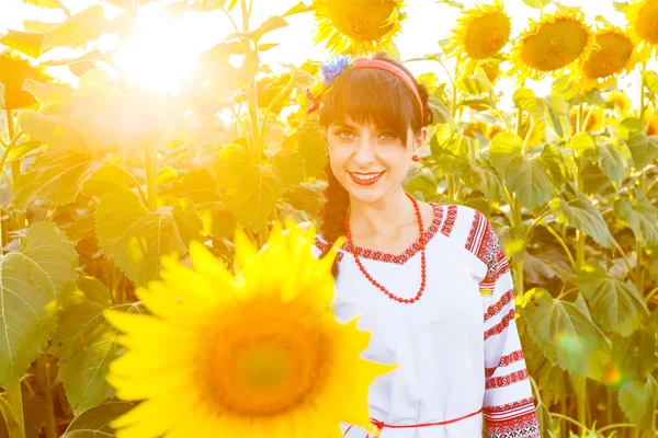 Beautiful smiling girl in embrodery on a sunflower field