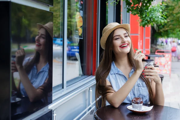Laughing beautiful girl in  outdoor cafe drinking coffee with mu
