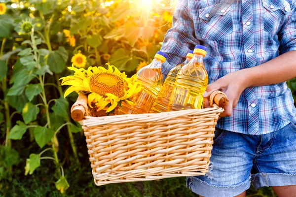 Basket with three bottles of sunflower oil in the hands of girl