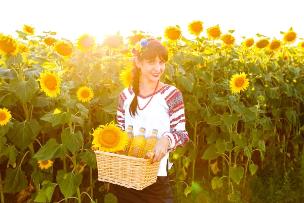 Smiling woman in embroidery holding a basket with sunflower oil