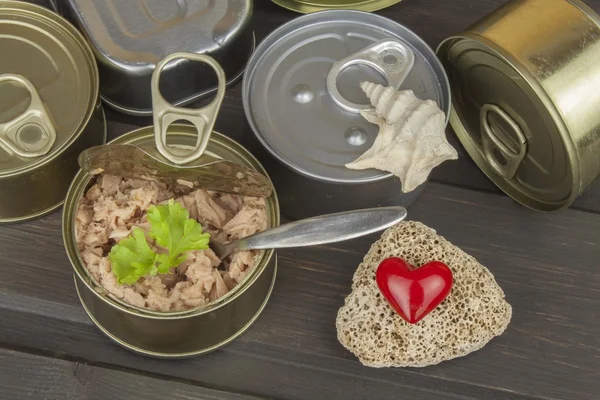 Tuna cans on a dark wooden table. Sales of canned fish. Diet food. Fishing industry.