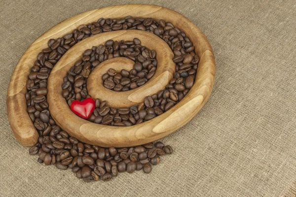 We love fresh roasted coffee. Roasted coffee beans in a wooden spiral on the canvas background. Fresh roasted coffee. Preparing for brewing coffee.