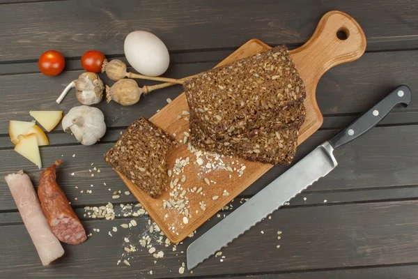 Freshly baked whole wheat bread. Preparing homemade breakfast. Various ingredients for the meal. Sliced bread on cutting board. Advertising on the bakery.