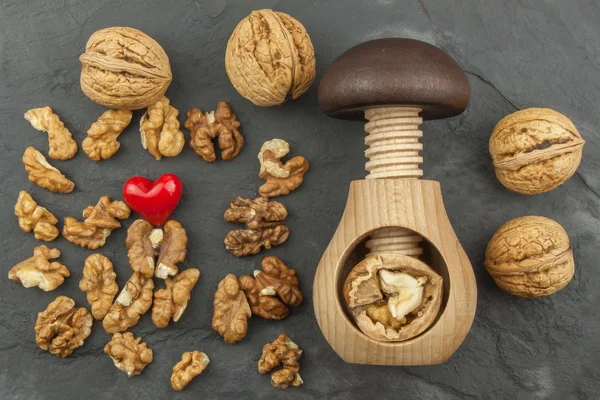 Walnut kernels and whole walnuts on slate.  Walnuts and wooden nutcracker. We like walnuts. Advertising on walnuts.