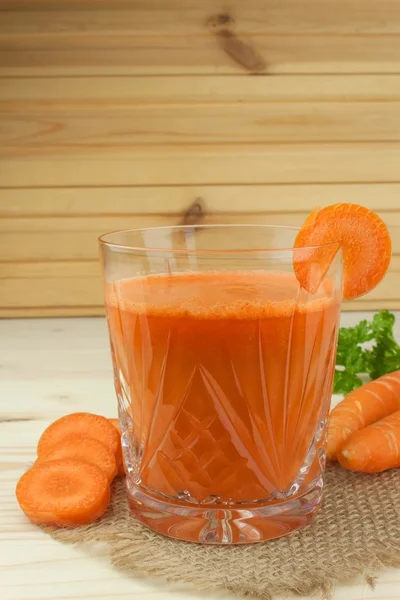 Glass of carrot juice and carrots on the wooden table. Healthy juice full of vitamins and fiber. Diet Food. Carrot segments on a wooden background.