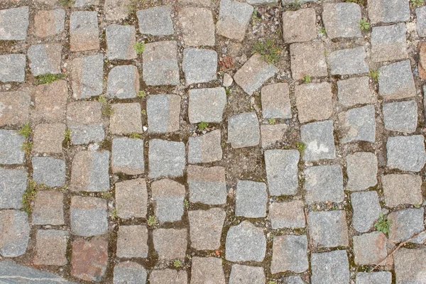 Old stone paving on the street. Detail of historic granite tiles.