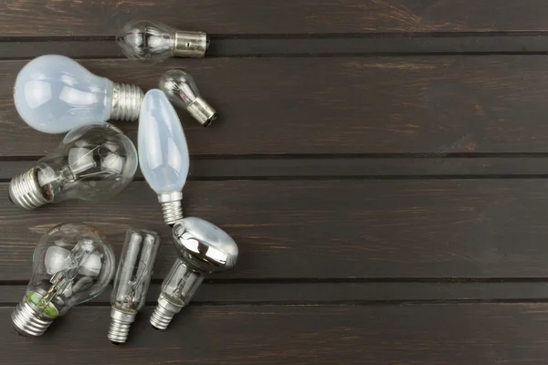 Different types and shapes of incandescent light bulbs on a wooden background. Sales of light bulbs. Advertising for lighting equipment.