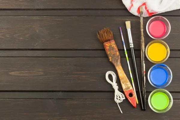 Brushes and paint on a wooden table. Painter tools. Workshop painter. Needs painting. Sales painting needs. Clutter on the workbench. Sales of color. Advertising on painting.