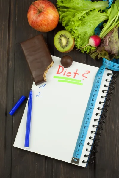 Preparing for the diet program. The decision to initiate dieting. Planning of diet. Notebook measuring tapes and pen on wooden table.