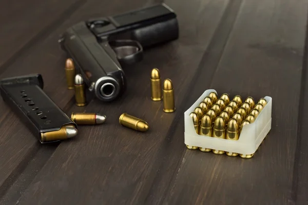 Handgun with ammunition on a dark wooden table. Sales of weapons and ammunition. Advertising on ammunition. New gun and ammunition. Grocery ammunition. The supply of ammunition for the defense.