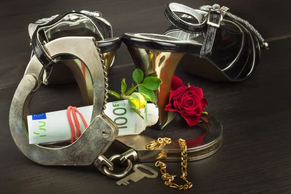 Metal handcuffs and women\'s shoes. The concept of sexual games. Violence against women, prostitution. Handcuffs for a sex game. Advertising sex shop.