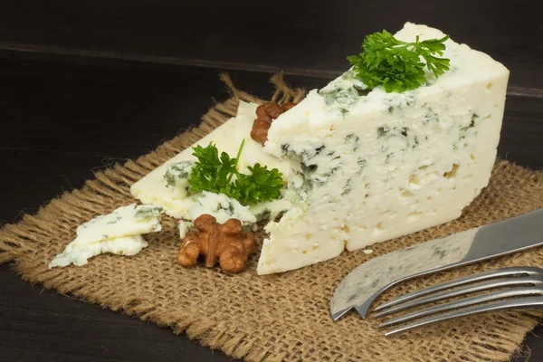 Danish blue. Blue cheese close up on an old wooden table. Preparing food blue cheese. Cheese on the kitchen table. Noble rot. Cheese with mold delicacy.