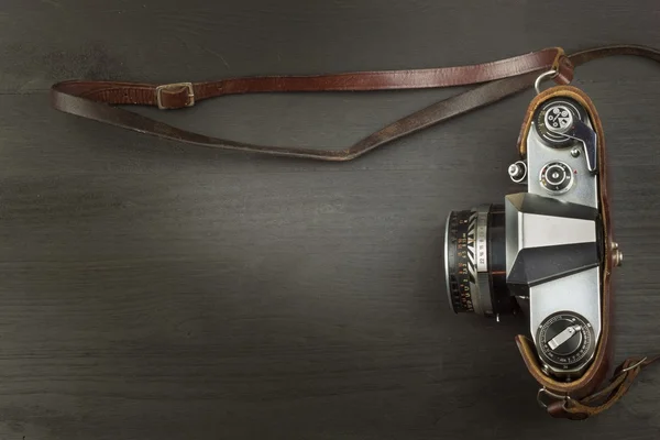 Old camera in a leather case on a black wooden background. The camera of the past. Advertising for the sale of the camera. For roll film camera. Equipment artistic photographer.