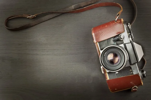 Old camera in a leather case on a black wooden background. The camera of the past. Advertising for the sale of the camera. For roll film camera. Equipment artistic photographer.