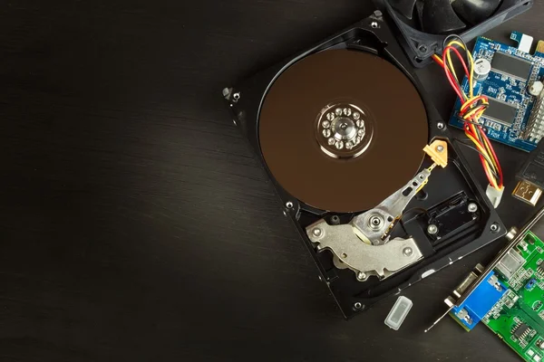 Open hard drive on a black wooden background. Production of computers. Electronics store. Backing up data on your computer. Modern technology. Place for your text.