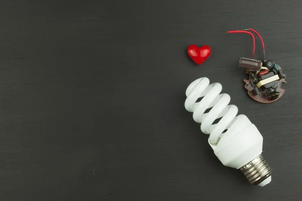 Energy saving lamp on black wooden background. Sales of light bulbs. Advertising for energy-saving bulbs. Place for your text.