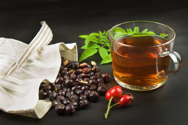 Drink from the hips in glass cup on wooden background. Traditional treatment of colds and flu. Medicinal plants.