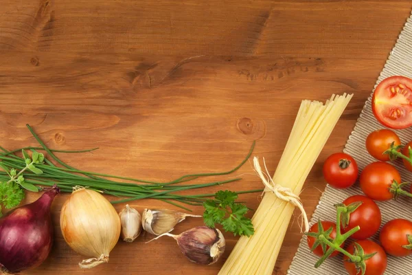 Raw pasta with tomatoes and parsley on a wooden background. Preparation diet food. The recipe for a simple dinner. Traditional pasta with vegetables.