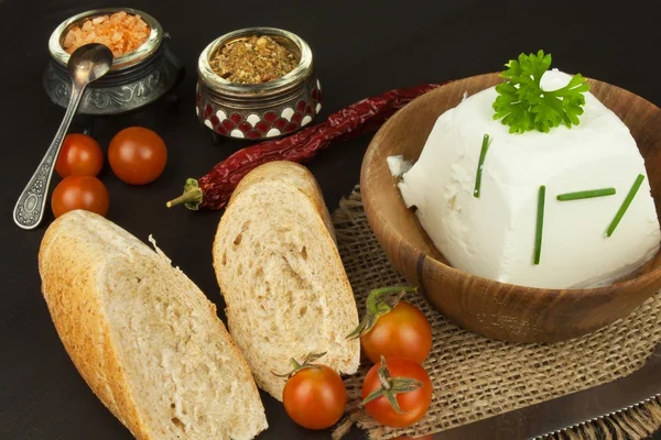 Goat cheese with fresh tomatoes on wooden table. Fresh cheese and pastries. Diet food. Goat cheese with vegetables.