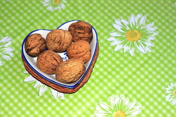 Whole walnuts in a bowl in the shape of a heart on the table