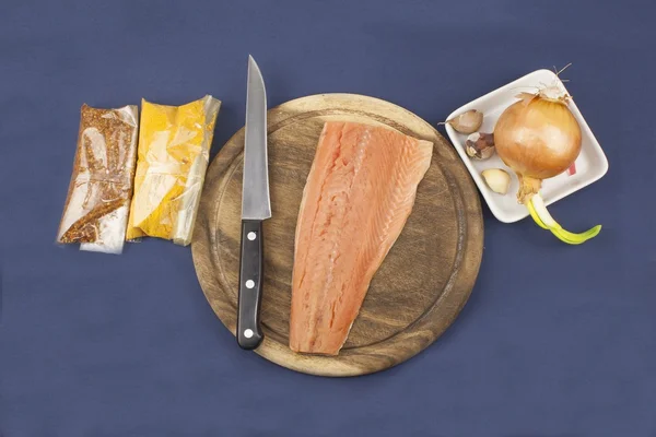 Preparation of frozen salmon, homemade dressing, salmon on a wooden chopping board