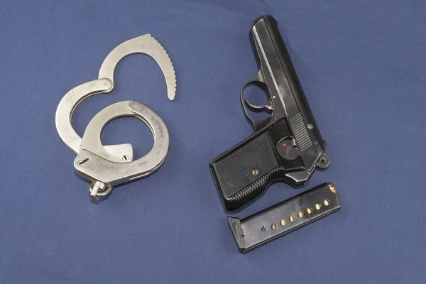 Gun, magazine and police handcuffs lying on the table