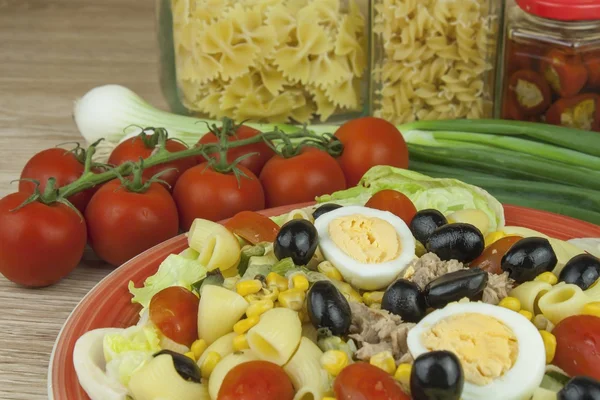Refreshing summer dish, pasta with tuna, vegetables, olives and egg. Healthy food for athletes.