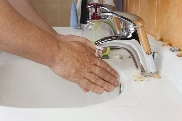 Man washing his hands in the sink. Hygiene in the home bathroom.