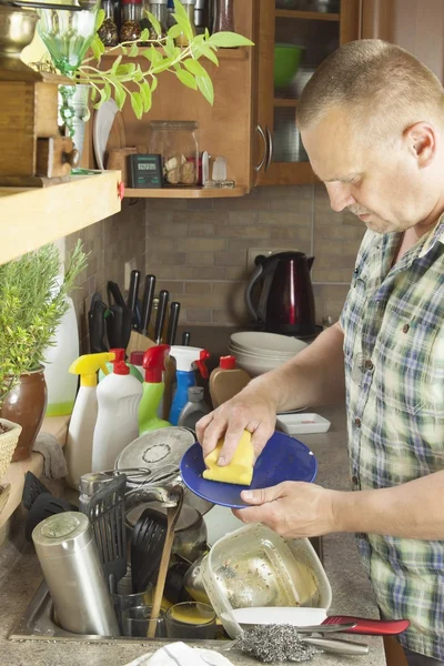 Man washing dirty dishes in the kitchen sink. Domestic cleaning up after the party.