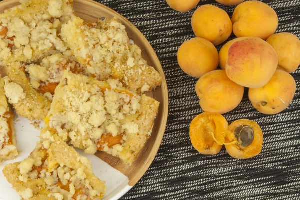 Homemade apricot cake on a plate. Freshly picked apricots on a wooden table. Homemade dessert of summer fruits.