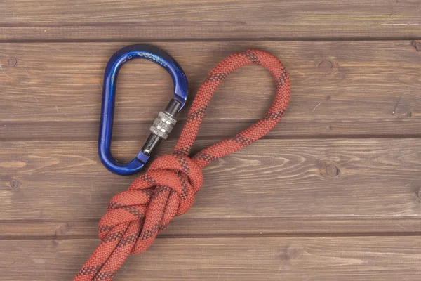 Figure eight knot with climbing carabiner on wooden background. The concept of selling advertising space for climbing equipment.