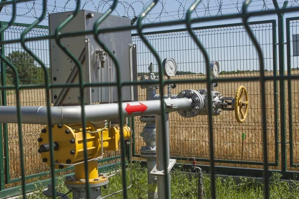 Checkpoint pipeline, pressure measurements and flow of natural gas. Closeup of pressure meter on natural gas pipeline. Fenced station located in the fields against blue sky.