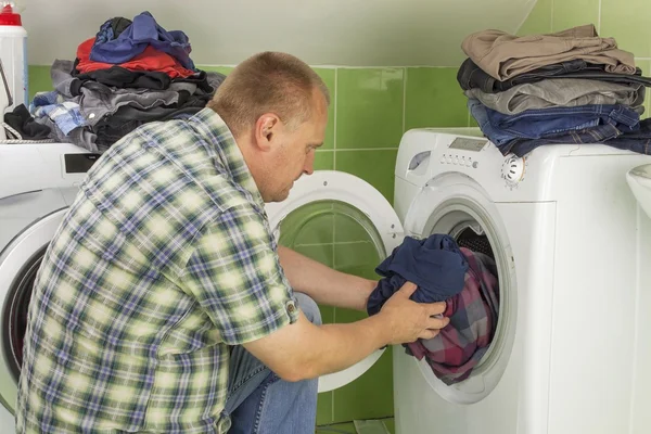 Man washes clothes in the washing machine. Housework men. Man helping his wife when washing clothes. The division of housework. Man Near The Washing Machine.