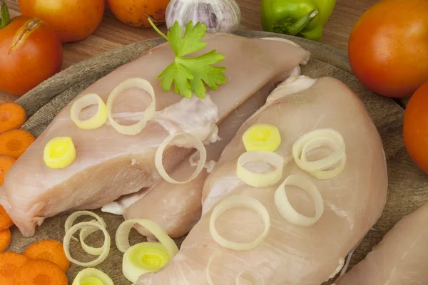 Fresh raw chicken fillet and vegetables prepared for cooking. Fresh raw chicken breasts. Preparing chicken at a summer barbecue. Cooking with fresh dietary ingredients.