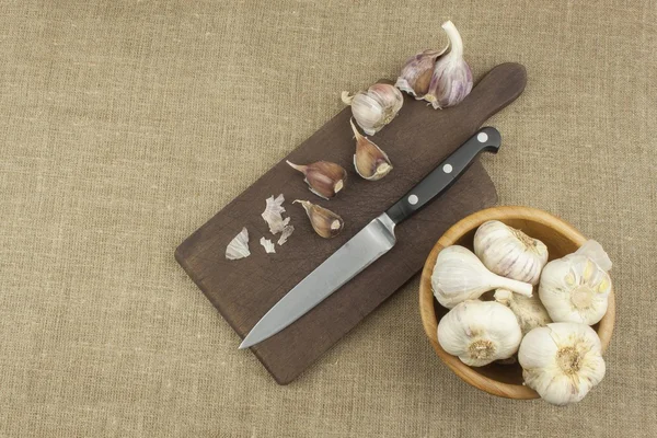 Knife, Garlic and a Cutting Board. Chopped garlic and a knife on a wooden board. Garlic bulbs on wooden chopping board