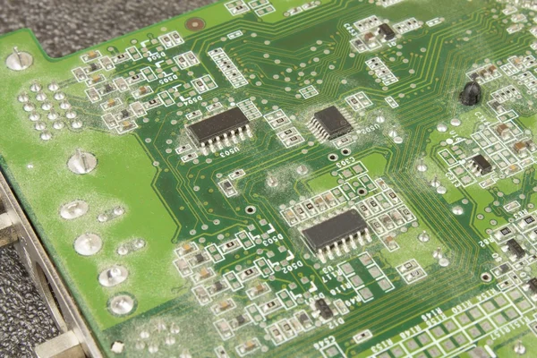 A dusty green computer component. Detail of a dusty computer mainboard. Electronic components on the printed circuit board.