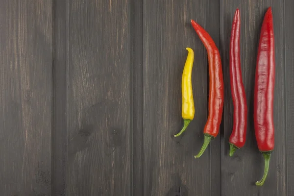 Chili peppers on a wooden kitchen table. Homework spicy food. Decorations for the menu. Place for text. Fresh chilli on old wood background.