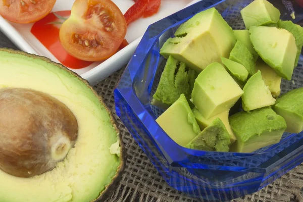 Preparation of dietary avocado salad. Fresh ripe avocado on a wooden background. Food background with fresh organic avocado. Avocado on a dark wood background.