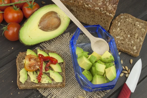 Preparation of dietary avocado salad. Fresh ripe avocado on a wooden background. Food background with fresh organic avocado. Avocado on a dark wood background