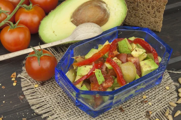 Preparation of dietary avocado salad. Fresh ripe avocado on a wooden background. Food background with fresh organic avocado. Avocado on a dark wood background