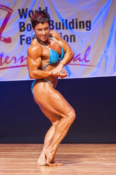 Female bodybuilder flexes her muscles to show her physique