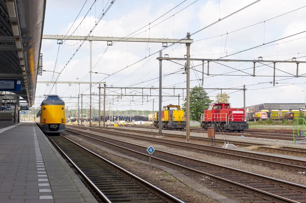 Platform of train station with yellow and red train locomotives