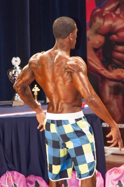 Male fitness contestant shows his best back pose on stage