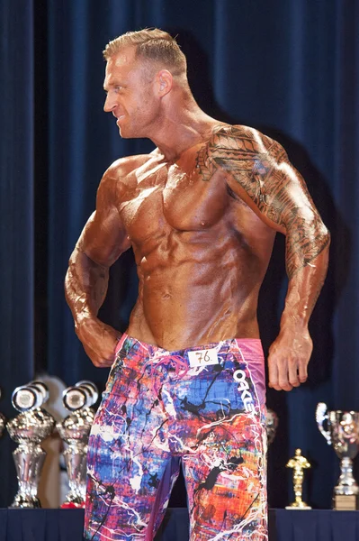 Male bodybuilder shows his best chest pose on stage