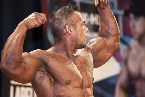 Male bodybuilder shows his front double biceps