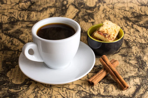 Cup of hot espresso coffee, and cookie on a map