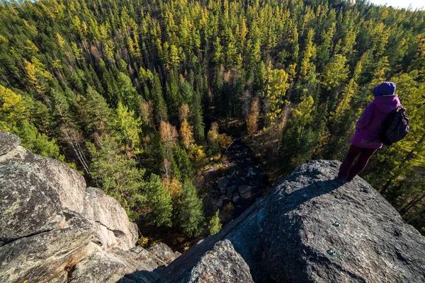 Girl stands high on a cliff