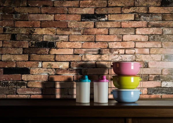 Colorful tiffin carrier and plastic bottles on wooden cupboard w