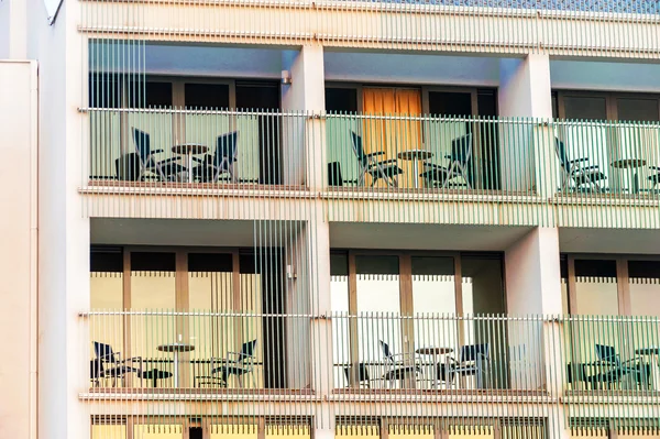 Pattern of hotel room balconies in modern building with warm sunset light falling on facade