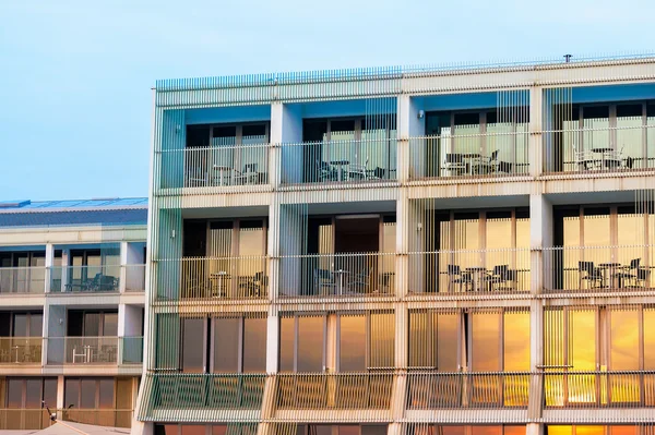 Pattern of hotel room balconies in modern building with warm sunset light falling on facade